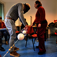 Practice phase of the workshop: people standing around having a hands-on experience with a string and hanging balls